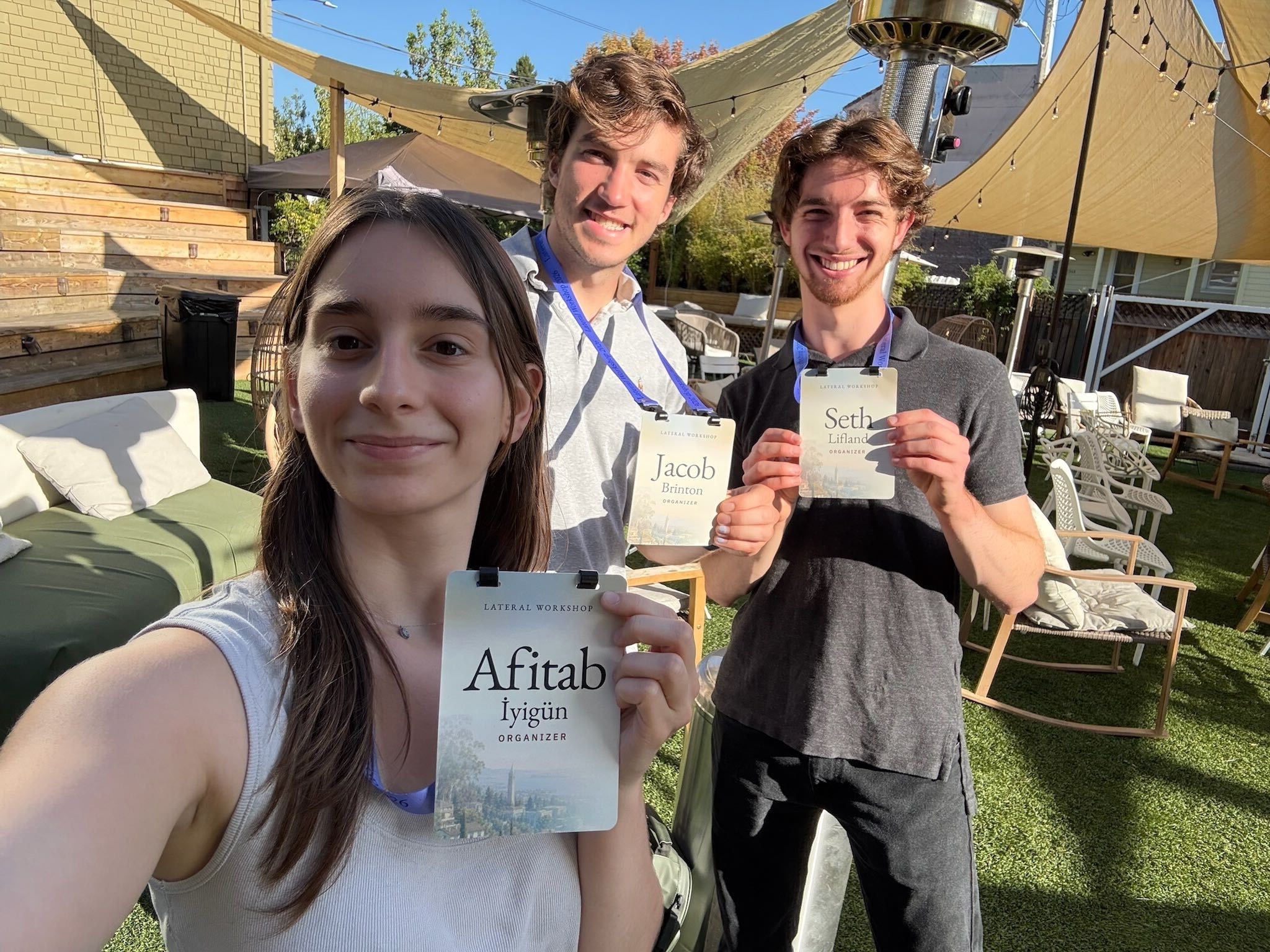 Three Lateral Workshop organizers holding their name badges outdoors
